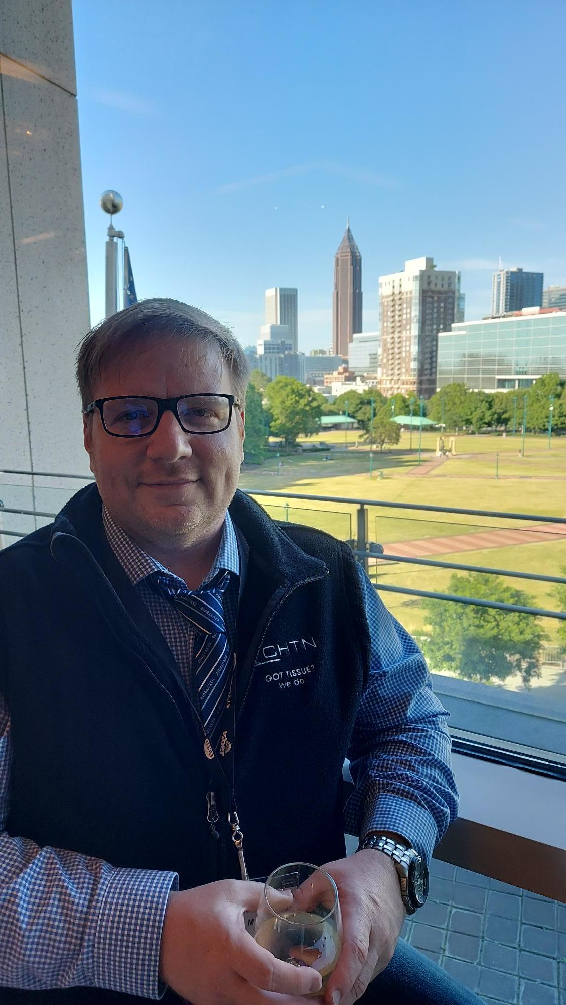 Zack-sitting-at-the-conference-with-the-Atlanta-skyline-behind